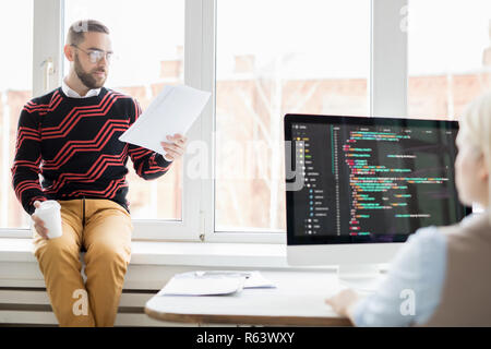 Pensive manager reading report to programmer Stock Photo
