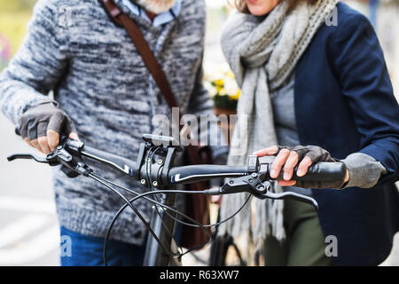 A midsection of senior couple with electrobike standing outdoors in town. Stock Photo