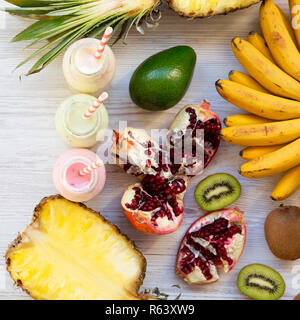 Fruit smoothies of various tastes in glass jars on white wooden surface, top view. Overhead, from above. Stock Photo