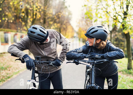 Active senior couple with electrobikes standing outdoors on a road in nature. Stock Photo