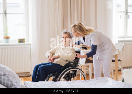 A health visitor talking to a senior woman in wheelchair at home. Stock Photo
