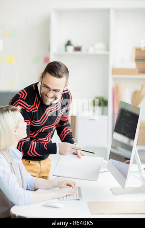 Smiling manager inspecting work of coder Stock Photo