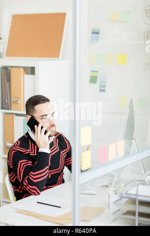 Serious handsome marketing expert talking to customer on phone Stock Photo
