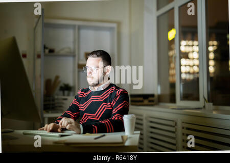 Young man working late in office Stock Photo