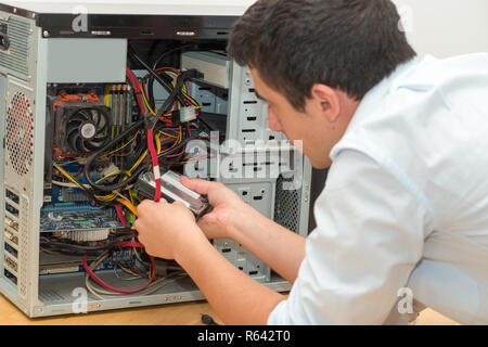 Young technician working on broken computer in his office Stock Photo