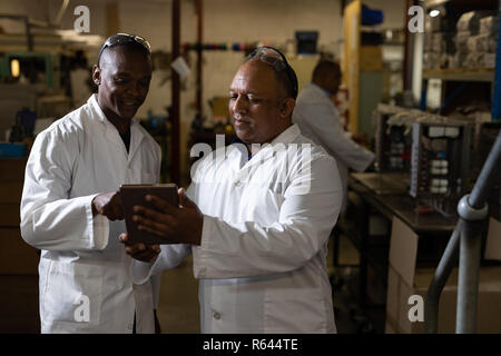 Male workers discussing over a digital tablet in glass factory Stock Photo