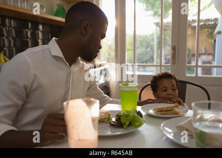 Father feeding food to his son in kitchen Stock Photo