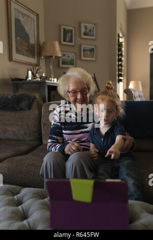 Grandmother and granddaughter making video call on digital tablet in living room Stock Photo