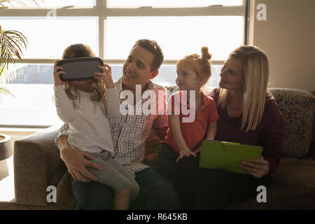 Girl using virtual reality headset with family in living room Stock Photo