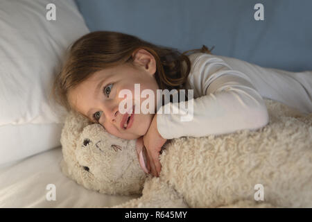 Girl relaxing with teddy bear in bedroom Stock Photo