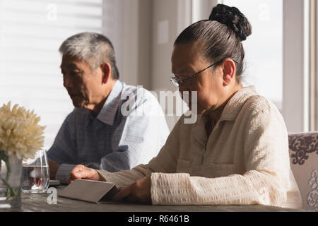 Senior woman using digital tablet on dining table Stock Photo