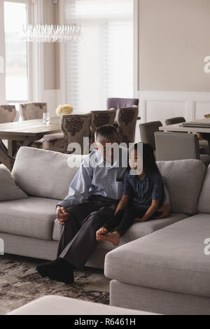 Grandfather and granddaughter interacting with each other on sofa in living room Stock Photo