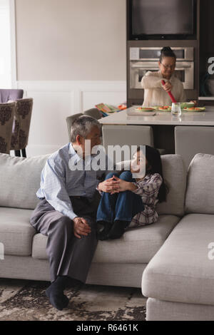 Grandfather and granddaughter interacting with each other on sofa in living room Stock Photo
