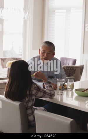 Grandfather and granddaughter interacting with each other on dining table Stock Photo
