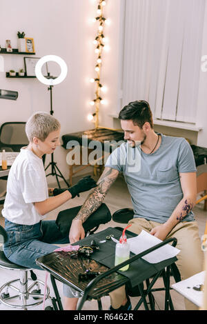 Short-haired blonde woman working with tattoo sleeve Stock Photo