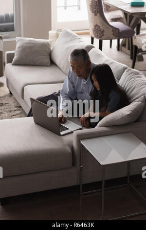 Grandfather and granddaughter using laptop on sofa in living room Stock Photo