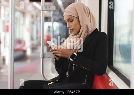 Woman using mobile phone while travelling in train Stock Photo