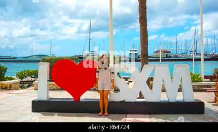The woman posing near sign and statue I love St Martin in Marigot, St .Maarten Stock Photo