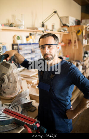 Mature Carpenter Posing in Sunlit Workshop Stock Photo