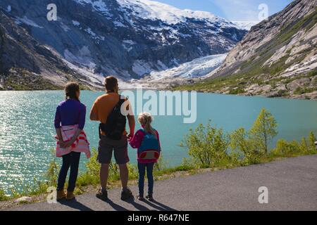 father and children are looking at the Nigardsbreen glacier at Norway Stock Photo