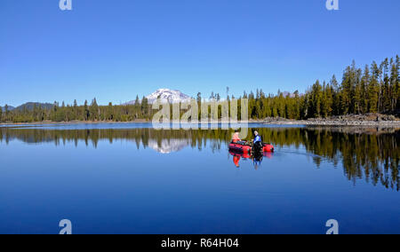 Two fishermen troll for rainbow and brown trout in Lava lake, a deep mountain lake along the Cascade Lakes Highway in the Cascade Mountains of central Stock Photo