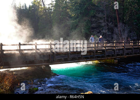 A morning mist rises from the Metolius River in the Cascade Mountains of Oregon, while two hikers enjoy the view. Stock Photo