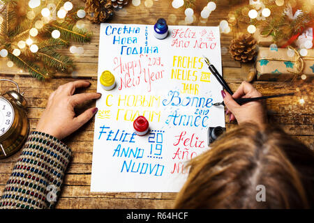 Person writing a Happy new year card in various languages Stock Photo