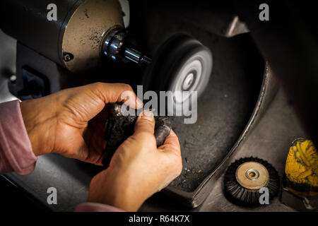 Jeweler polishes a gold ring on a bench grinder in an authentic jeweller's workshop Stock Photo