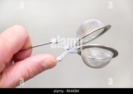 Tea strainer in hand close-up on a light background. Stock Photo
