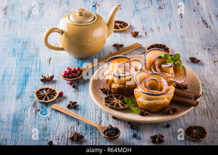 Horizontal photo with crispy dessert. Sweet is made from apple slices and puff pastry. Dessert is called apple roses. Several herbs and spices are spi Stock Photo