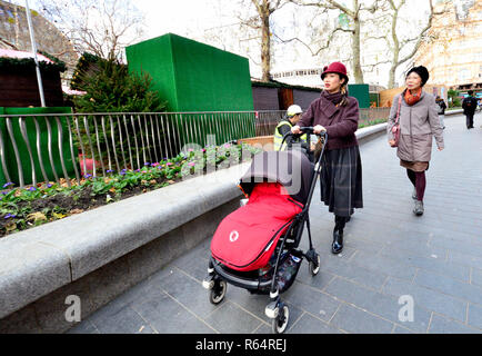 Japanese woman pushing a buggy in Leicester Square, London, England, UK. Stock Photo