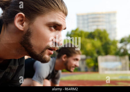 Photo of young two twins sportsmen brothers ready to run outdoors. Stock Photo