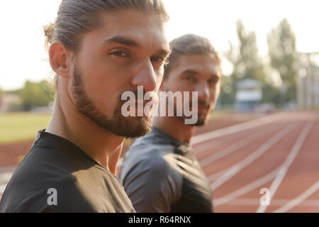 Photo of young two twins sportsmen brothers standing at the stadium outdoors. Stock Photo