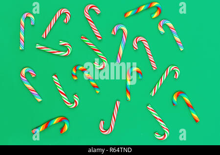 Christmas art background with scattered multi coloured sweets candies Santa's chopsticks on a green background, holiday concept. Flat lay. Copy space. Stock Photo