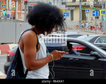 Street scene: young man using his smartphone, texting, listening music, outdoors Stock Photo