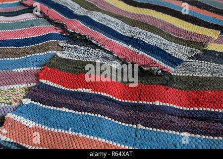 Traditional rustic striped multi-colored rug. Bright textile. Village eco concept. Selective focus Stock Photo