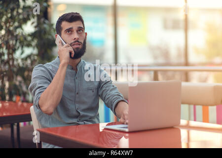 Excited happy bearded freelancer reading email with results about victory in modern online contest sitting at laptop computer at table. Stock Photo