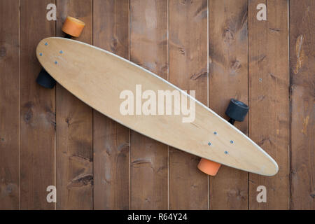 Old skateboard as signboard with copy space on a wooden wall as background Stock Photo