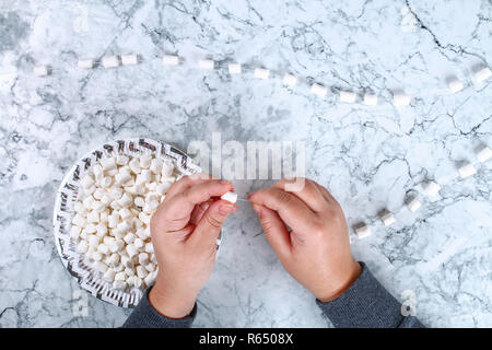 Diy marshmallow garland. Guide on photo how to make a decorative marshmallow garland, threads, needles and branches with your own hands. Handmade Chri Stock Photo