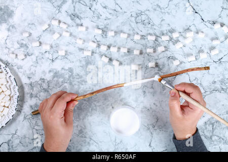 Diy marshmallow garland. Guide on photo how to make a decorative marshmallow garland, threads, needles and branches with your own hands. Handmade Chri Stock Photo