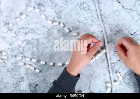 Diy marshmallow garland. Guide on photo how to make a decorative marshmallow garland, threads, needles and branches with your own hands. Handmade Chri Stock Photo