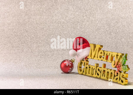 Santa Claus hat put on a golden word Merry Christmas with a Christmas Tree snowflakes pattern ornament ball on a glitter silver snow background. Stock Photo