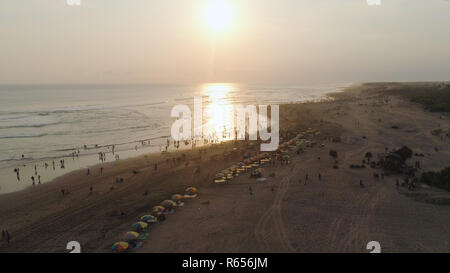 sandy beach parangtritis near ocean with big waves, people in tropical resort at sunset. Yogyakarta, Indonesia. aerial view seascape, ocean and beautiful beach. Travel concept. Indonesia, jawa Stock Photo