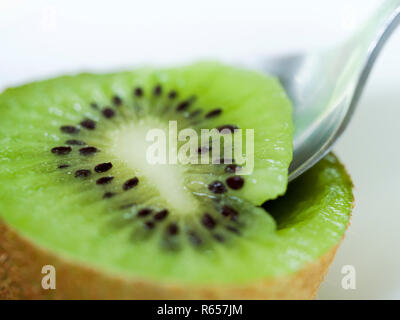 Close up of spoon taking centre of freshly cut kiwi fruit Stock Photo