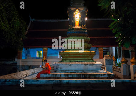 Young Monk with a mobile phone in Wat Sensoukaram buddhism temple in Luang Prabang city Laos Stock Photo