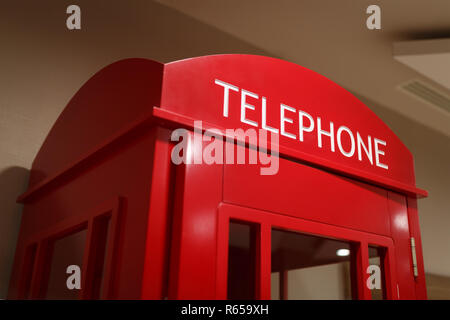 Traditional red telephone booth stands indoors as a symbol of London and the UK Stock Photo