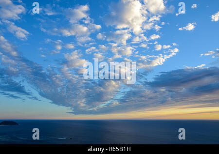 Sunset under white puffy clouds that appear to be radiating from the distance over Point Sur along California's Big Sur coast Stock Photo