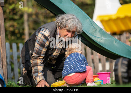 Grandpa playing with his granddaughter outside in playground Stock Photo