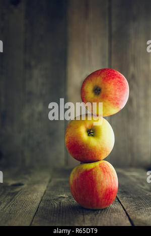 Balance. Three red apples one on another, wooden background Stock Photo