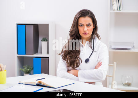 Angry female doctor looking at documents while working at her office. Stock Photo